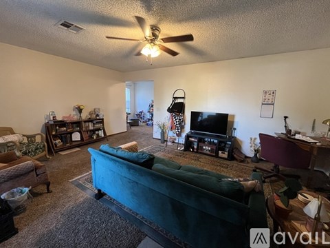 A living room with a green couch and a ceiling fan.