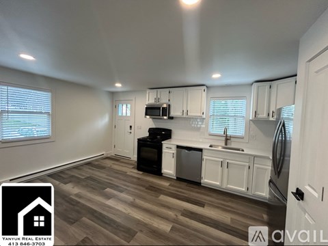 A kitchen with white cabinets and a wooden floor is available for rent.