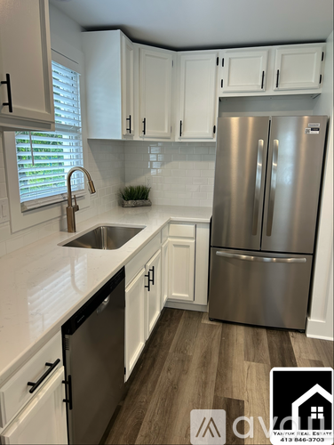 A kitchen with white cabinets and a stainless steel refrigerator.