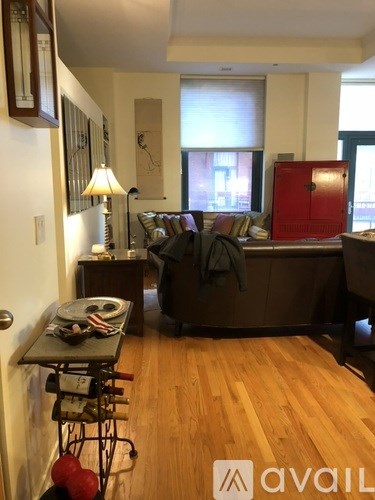A living room with a couch, a chair, a table with a bowl and a plate on it, and a red door.