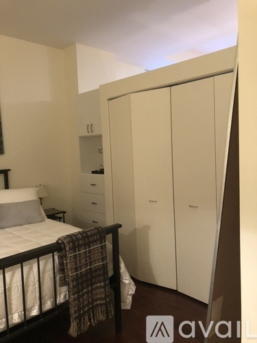 A bedroom with a bed, nightstand, and wardrobe.