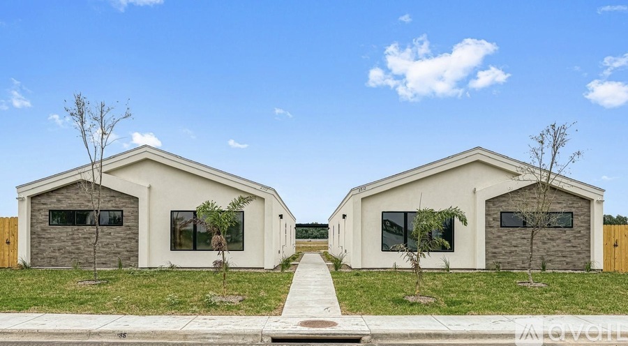 Two identical houses with a white facade and a yellow door are situated on a grassy area.