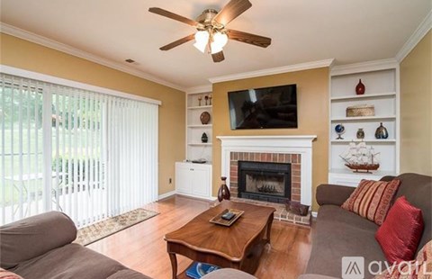 A living room with a fireplace and a television on the wall.