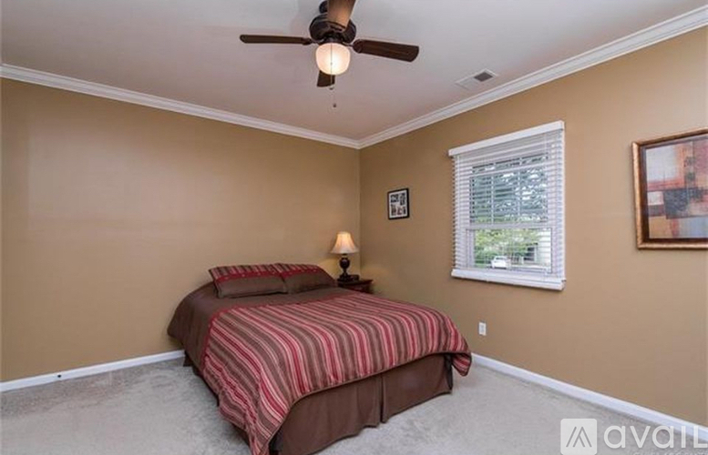 A bedroom with a bed, ceiling fan, and window.