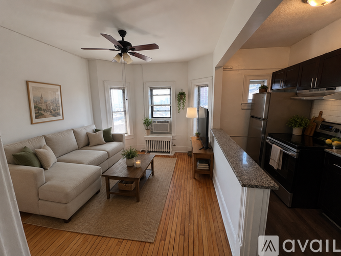A living room with a beige couch, a coffee table, and a ceiling fan.