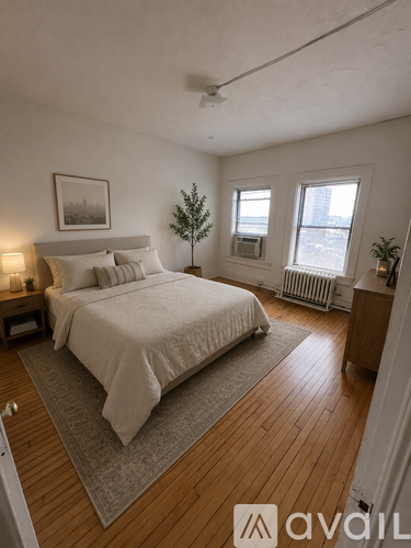 A bedroom with a large bed and a small tree in the corner.