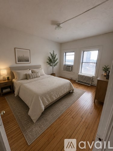 A bedroom with a large bed and a small tree in the corner.