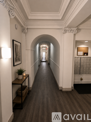 A long hallway with a plant on a table and a framed picture on the wall.