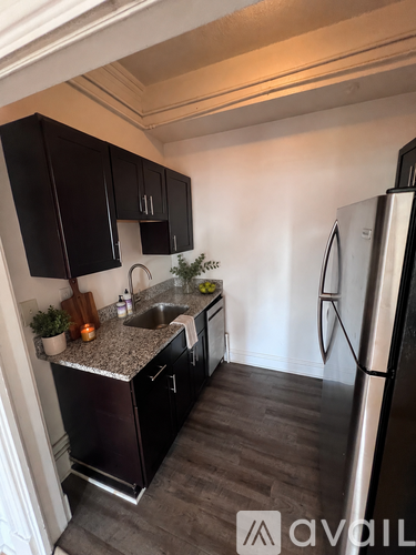 A kitchen with black cabinets and a stainless steel refrigerator.