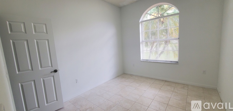 A room with a door and a window with a view of trees outside.