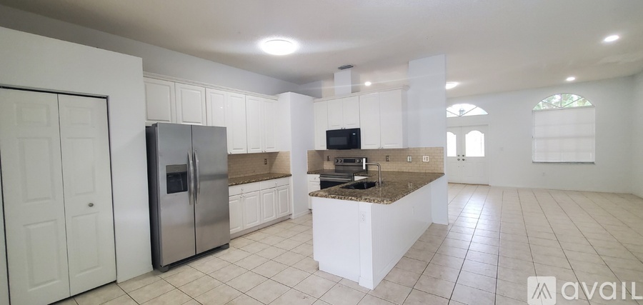 A kitchen with white cabinets and a stainless steel refrigerator.
