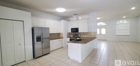 A kitchen with white cabinets and a stainless steel refrigerator.