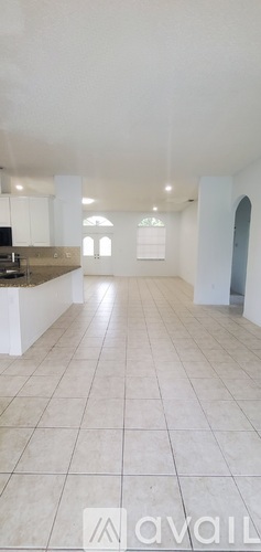 A spacious, empty room with white walls and tiled flooring.