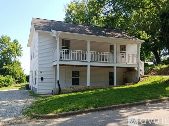 A white two-story house with a balcony on the second floor.