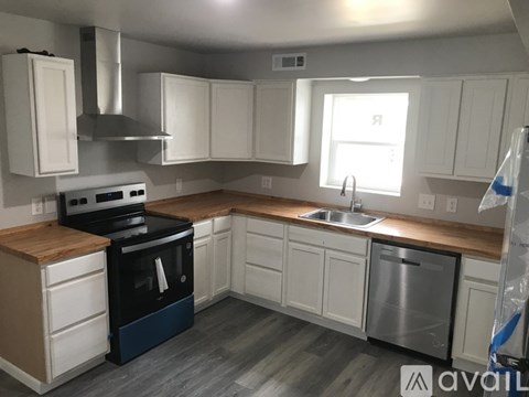 A kitchen with white cabinets and a wooden island.