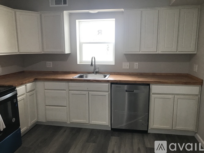 A kitchen with white cabinets and a wooden countertop.