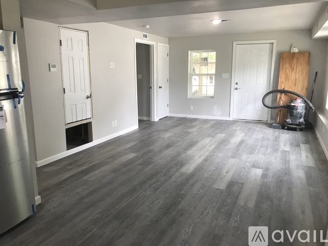 A spacious room with wooden flooring and white walls.