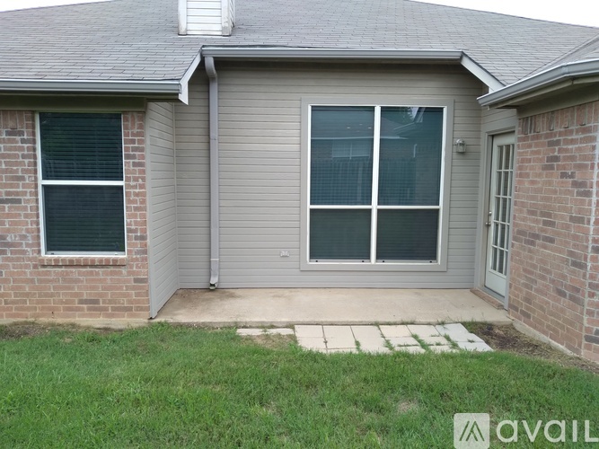 A house with a grey roof and a brick wall with a window and a door.