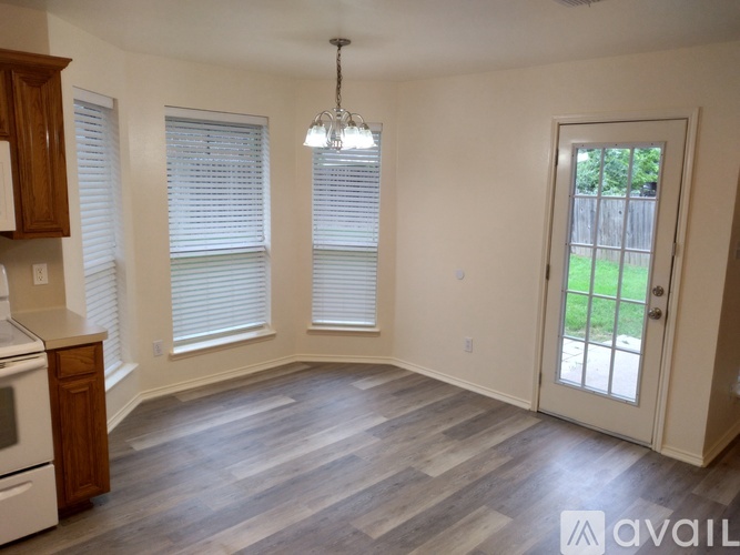A kitchen with a wooden cabinet and a window with blinds.