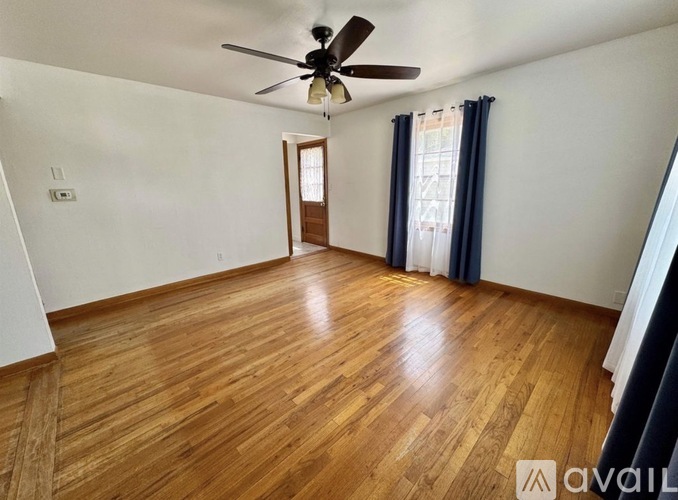 A room with wooden flooring and a ceiling fan.