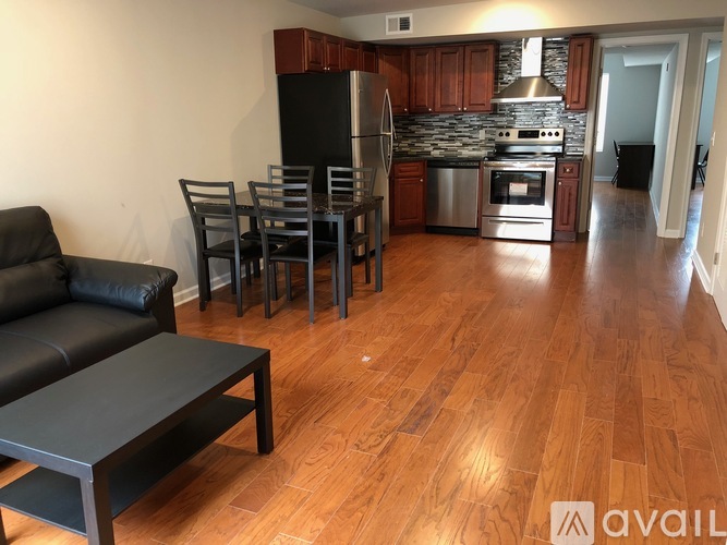 A kitchen with a black fridge, stove, and oven with a black table and chairs in front of it.