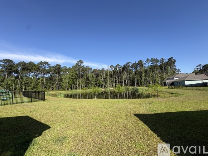 A grassy field with a fence and trees in the background.