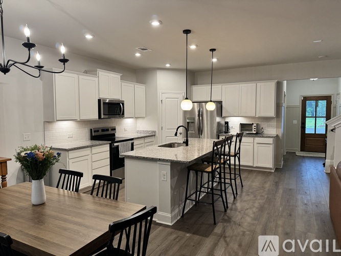 A modern kitchen with a wooden table and chairs, a microwave above the stove, and pendant lights hanging from the ceiling.