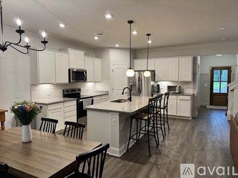 A modern kitchen with a wooden table and chairs, a microwave above the stove, and pendant lights hanging from the ceiling.