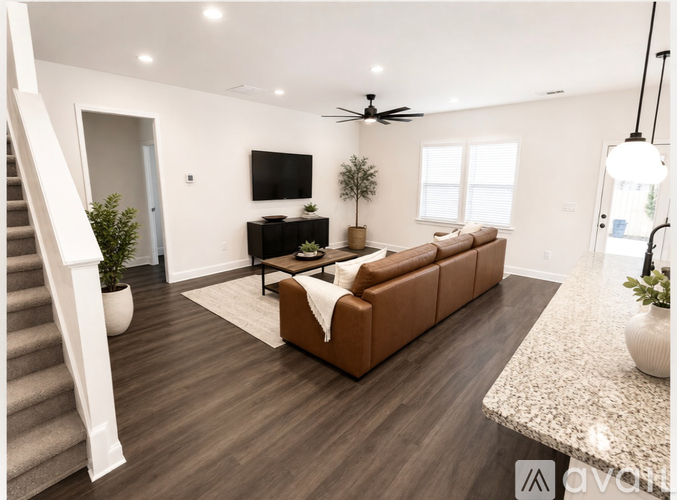 A living room with a brown sofa, a TV, and a ceiling fan.