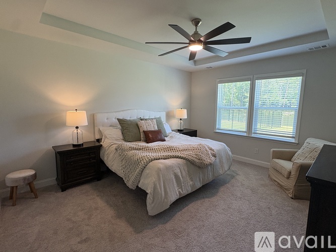A bedroom with a large bed, a ceiling fan, and a window with blinds.