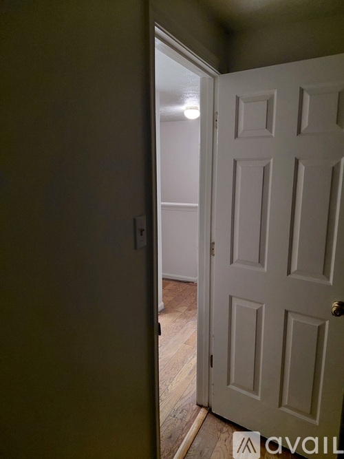 A white door is open to a room with wooden floors.