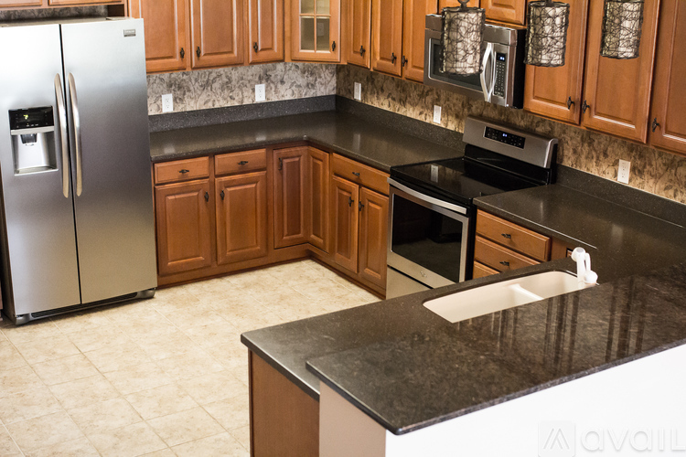 A kitchen with a black countertop and a stainless steel refrigerator.