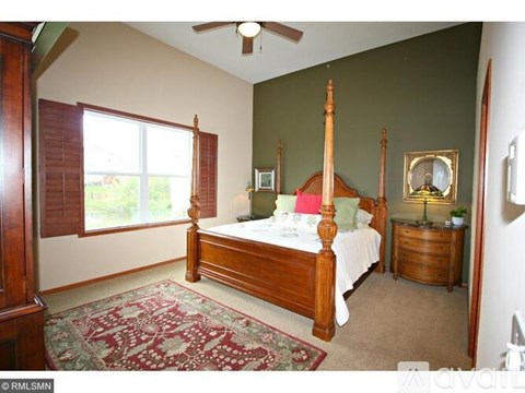 A bedroom with a four poster bed and a rug on the floor.