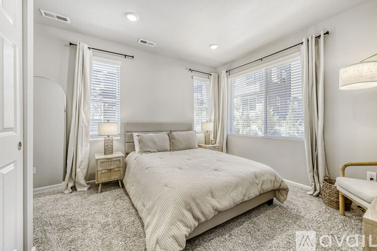 A bedroom with a large bed and a window with curtains.
