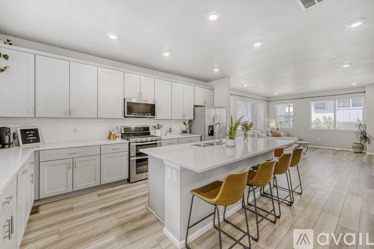 A modern kitchen with white cabinets and a long island with chairs.