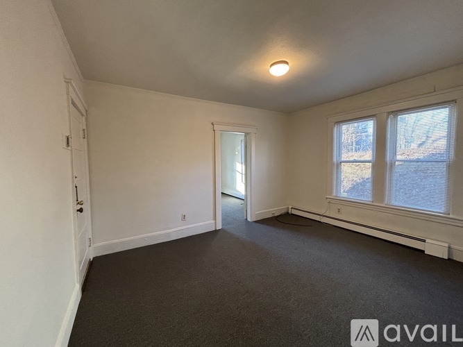 A room with a carpeted floor, a window, and a door.