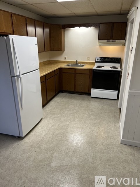 A kitchen with a white refrigerator and a black stove top oven.