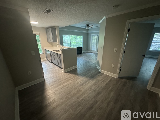 A spacious living room with a kitchen in the background.