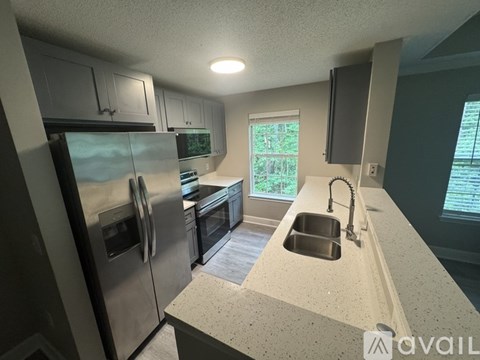 A kitchen with a stainless steel refrigerator and a granite countertop.