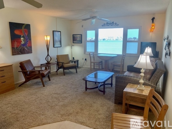 A living room with a carpeted floor and a ceiling fan.