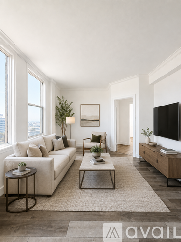 A living room with a white couch, a coffee table, and a television.