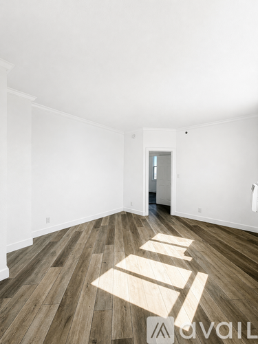 A room with wooden flooring and white walls.