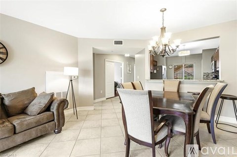 A living room with a brown couch and a dining table with chairs.
