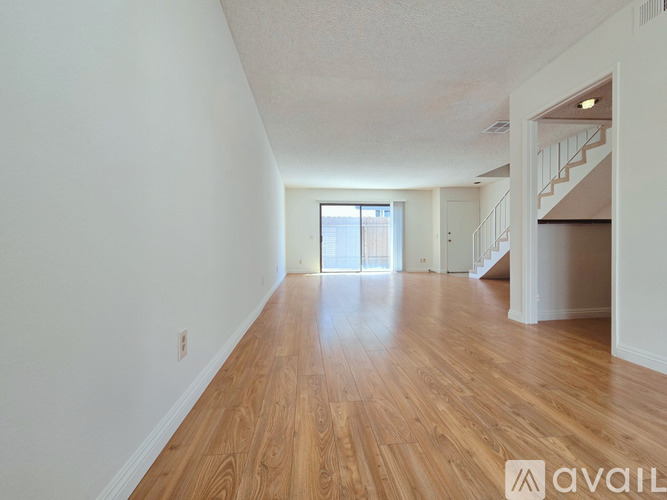A spacious room with wooden floors and white walls.