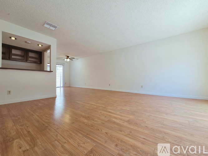 A spacious room with wooden flooring and a window.