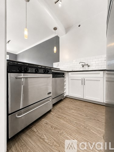 A modern kitchen with a stainless steel oven and white cabinets.