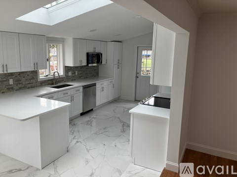 A kitchen with white cabinets and marble countertops.