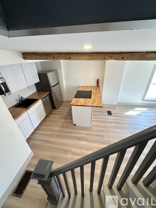 A kitchen with white cabinets and a wooden island.