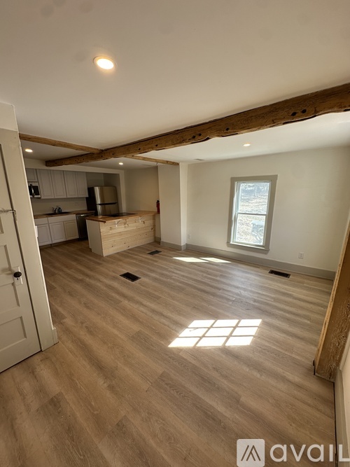 A room with wooden flooring and a window letting in sunlight.