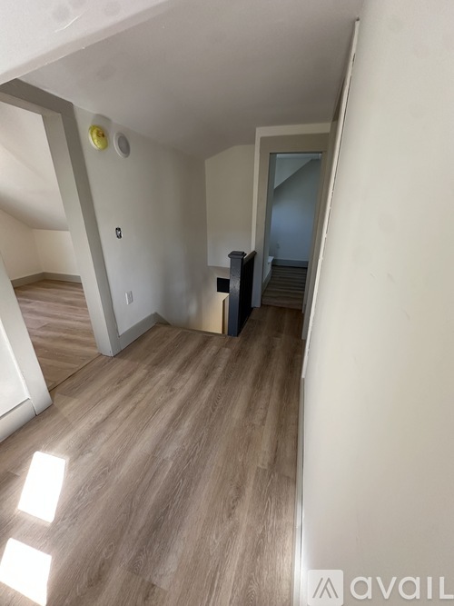 A room with wooden flooring and a white wall with a yellow object on it.